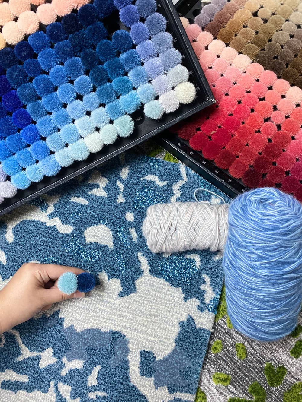 Handtufted carpet sample with yarn pom-pom color boards and yarn cones
