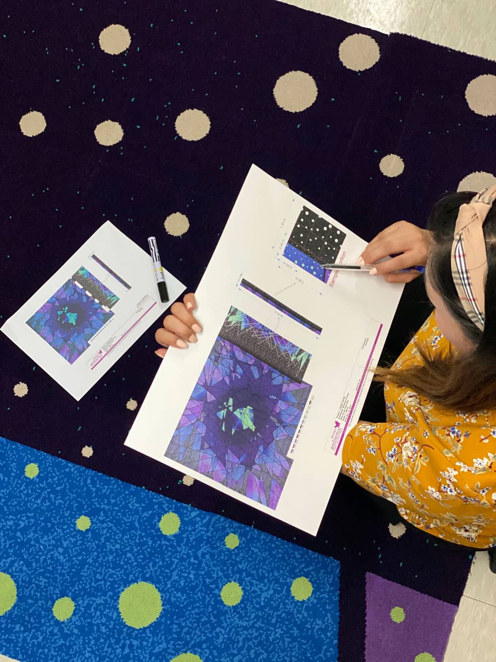 Designer reviewing custom carpet artwork and color samples on a printed rug